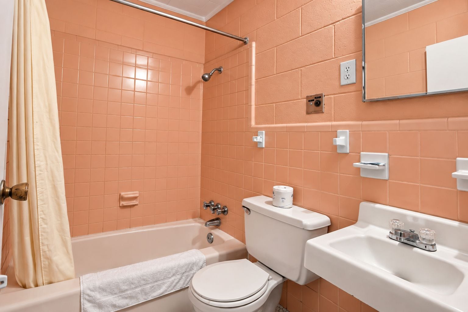 A bathroom with a bathtub, toilet, sink, and a shower area.