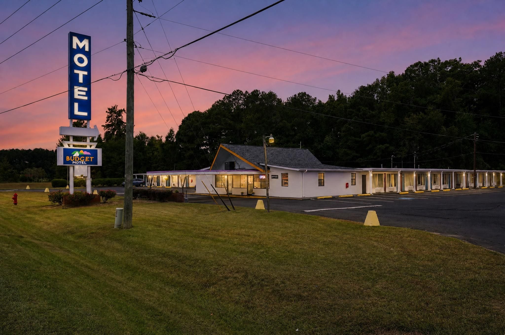 A motel with a large sign, a single-story building, and a parking lot.