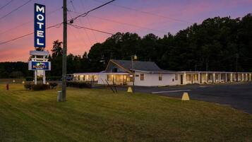 A motel with a large sign, a single-story building, and a parking lot.