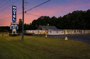 A motel with a large sign, a single-story building, and a parking lot.