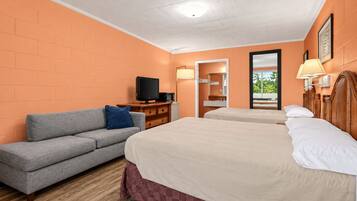 Una habitación de hotel con sofá, dos camas, televisor y espejo.