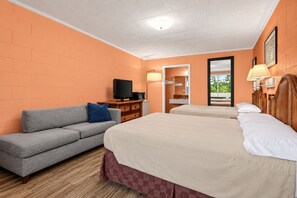Una habitación de hotel con sofá, dos camas, televisor y espejo.