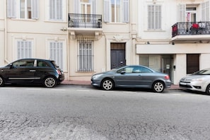 Eine Straße mit parkenden Autos und einem Gebäude mit Balkonen.