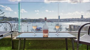 Ett bord med en flaska och två glas, med utsikt över en hamn med båtar och byggnader.