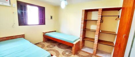 A room with a bed, a small table, a wardrobe, and a window.