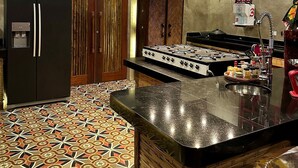 A kitchen with a gas stove, a refrigerator, and a patterned floor. - CRISTAL DA MATA (Caraíva)
