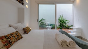 Een hotelkamer met een bed, kussens, uitzicht op de omgeving en een balkon.