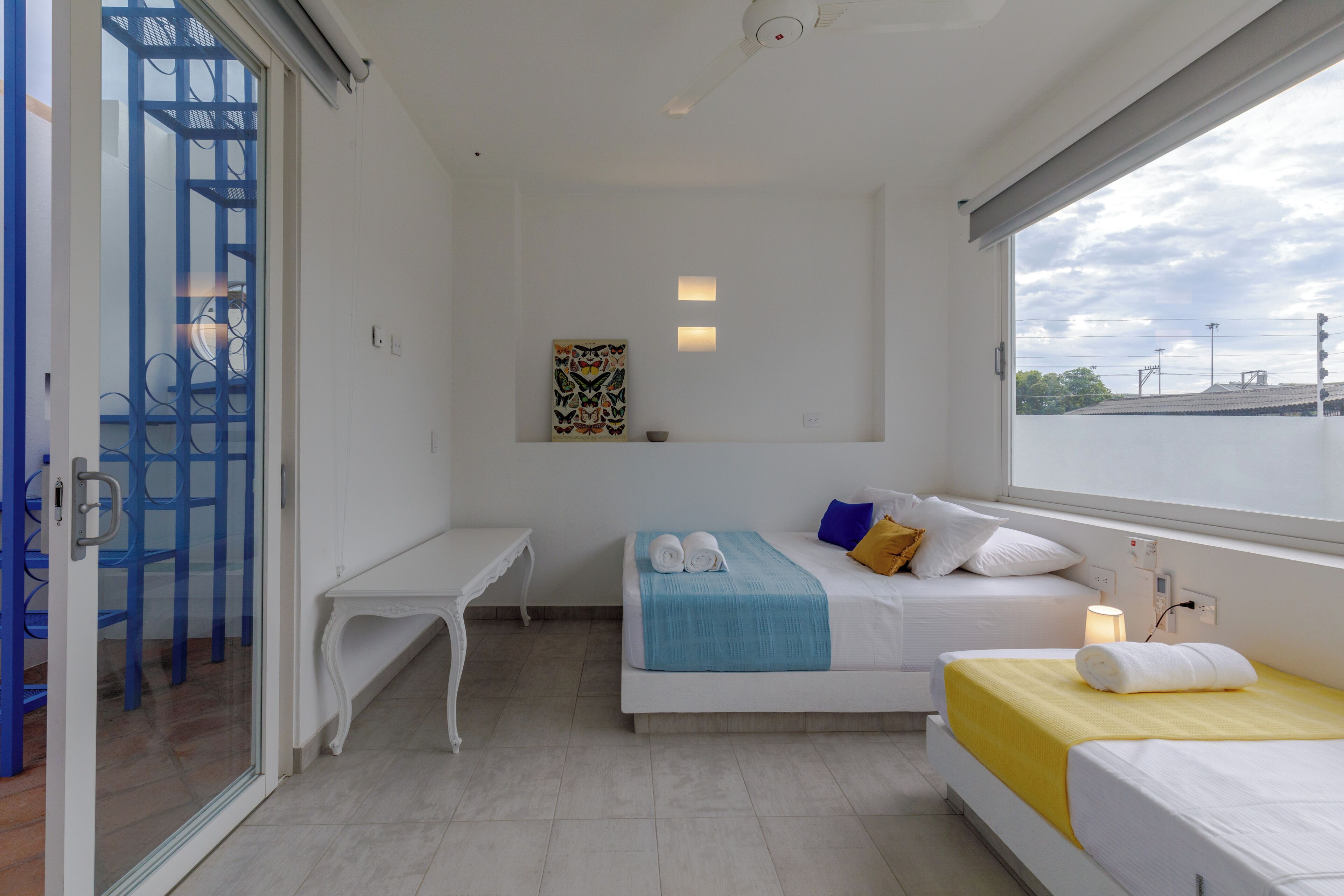 A hotel room with a bed, a desk, a window with a view, and a decorative wall piece.