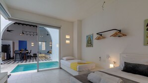 Een moderne hotelkamer met een bed, een klein bureau, een stoel, uitzicht op een zwembad en een zithoek.