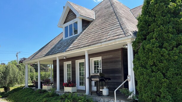 A house with a covered porch, a chimney, and a well-maintained garden.