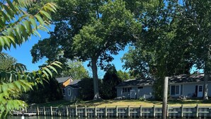 A wooden dock extending into a calm body of water, surrounded by trees and a residential area.