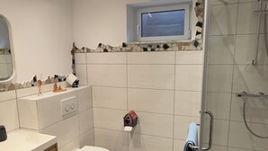 A modern bathroom with a toilet, sink, and shower. - MainNest Marktbreit - Cozy Apartment (Marktbreit)