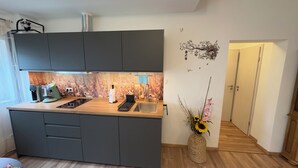 A modern kitchen with a built-in island, a coffee machine, and a vase with flowers. - MainNest Marktbreit - Cozy Apartment (Marktbreit)