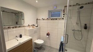 A modern bathroom with a toilet, sink, and shower. - MainNest Marktbreit - Cozy Apartment (Marktbreit)