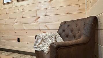Een kamer met houten lambrisering, een bruine fauteuil en drie ingelijste kaartjes aan de wand.