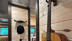 Un intérieur en bois avec une guitare, un lit et un chapeau accroché au mur.