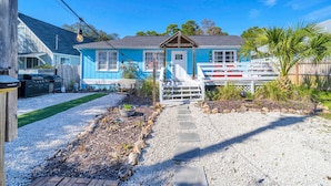 A blue house with a porch, a grill, and a pathway leading to the entrance. - The Blue Marlin (Panama City Beach)