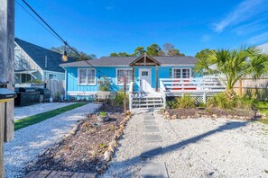 A blue house with a porch, a grill, and a pathway leading to the entrance. - The Blue Marlin (Panama City Beach)