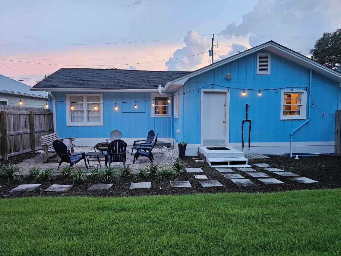 A blue house with a patio area, outdoor seating, and string lights.