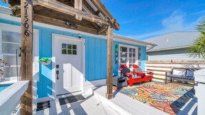 A blue house with a white door, a deck with red chairs, and a pool. - The Blue Marlin (Panama City Beach)