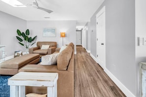 A modern living room with a sofa, a coffee table, and a plant. - The Beach Bunker (Panama City Beach)