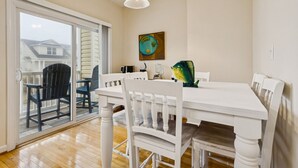 Et spiseområde med et hvidt bord og stole, et stort vindue og et billede på væggen.