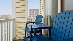 En balkon med to blå Adirondack-stole og en glasdør.