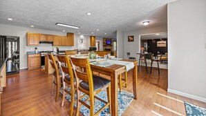 Een ruime keuken met houten kastjes, een eettafel gedekt voor vier personen en een groot aanrecht.