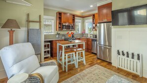 A compact kitchen with wooden cabinets, a stainless steel refrigerator, and a dining area with a table and two chairs. - Cozy Condo with a river views (Carrabelle)