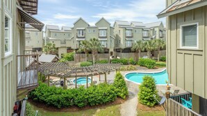 A residential complex with multiple apartment buildings, a swimming pool, and a covered patio area. - Cozy Condo with a river views (Carrabelle)