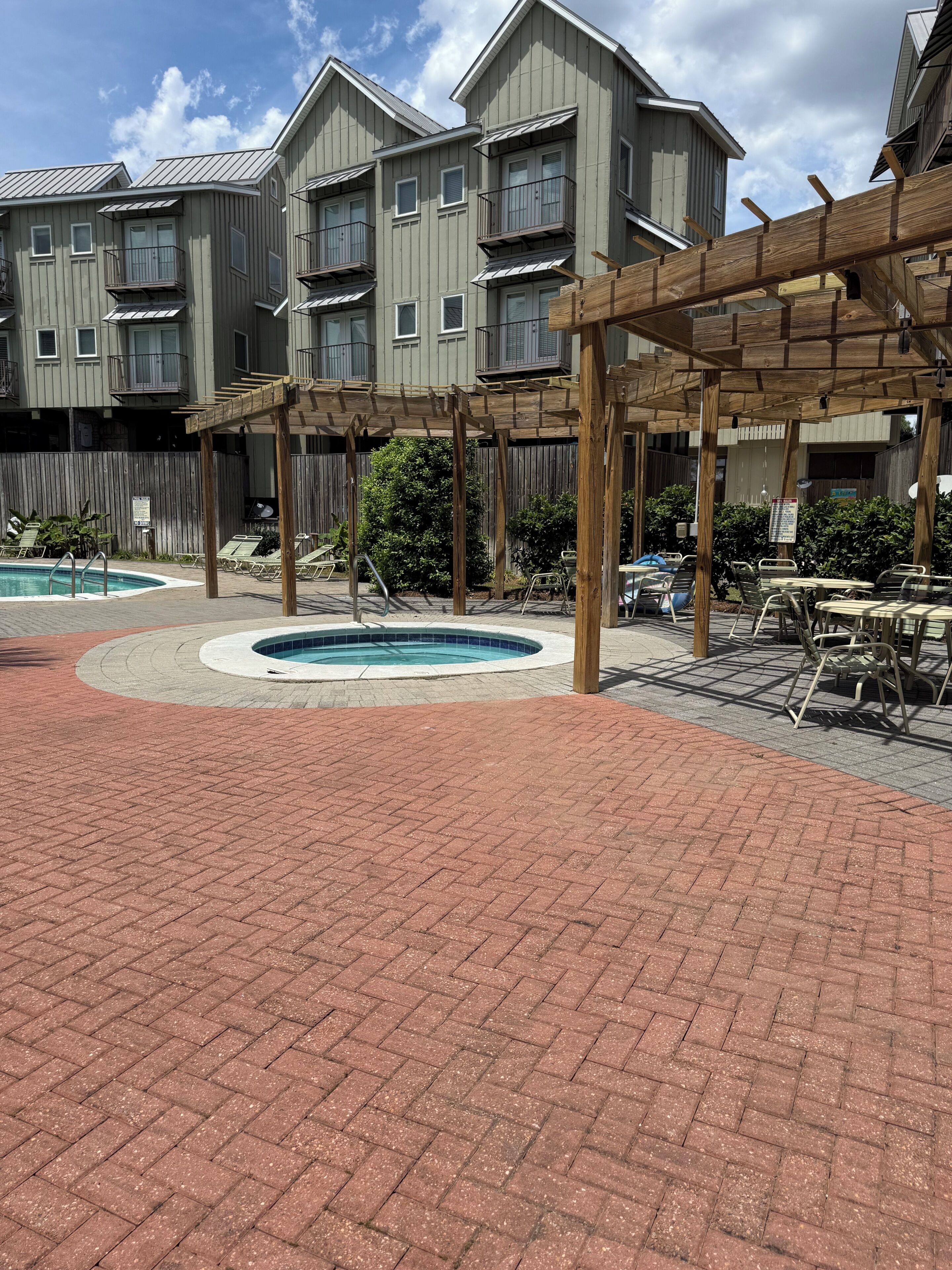 Une cour avec une piscine, des chaises longues et une pergola en bois.