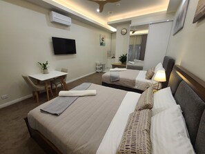 A hotel room with two beds, a desk, a chair, a TV, a mirror, and a ceiling fan. - Queen Room Victor harbor (victor harbor)