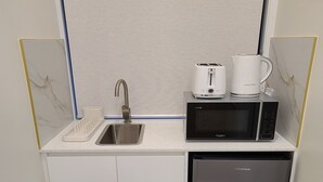 Et kompakt køkken med vask, mikroovn, brødrister og opvaskemaskine.