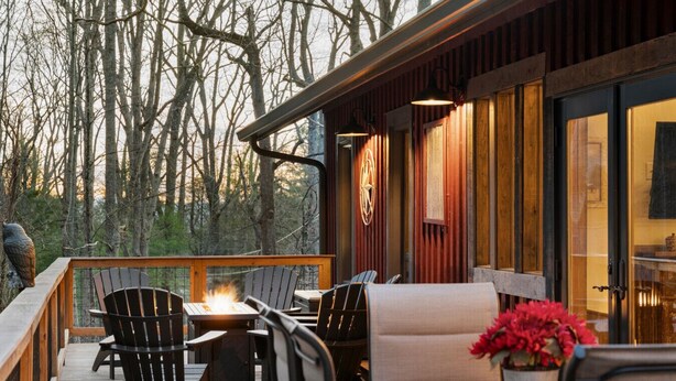 A deck with outdoor seating, a fire feature, and a view of trees. - 10 min to Asheville | Creekside, Fire Table, Games (Asheville)
