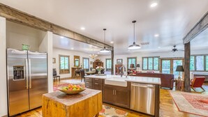 A spacious kitchen with a wooden table, stainless steel appliances, and a large island. - 10 min to Asheville | Creekside, Fire Table, Games (Asheville)