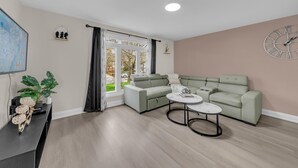A modern living room with a sectional sofa, a round coffee table, and a flat-screen TV.
