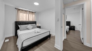 A bedroom with a bed, nightstands, a mirror, and a door leading to another room.
