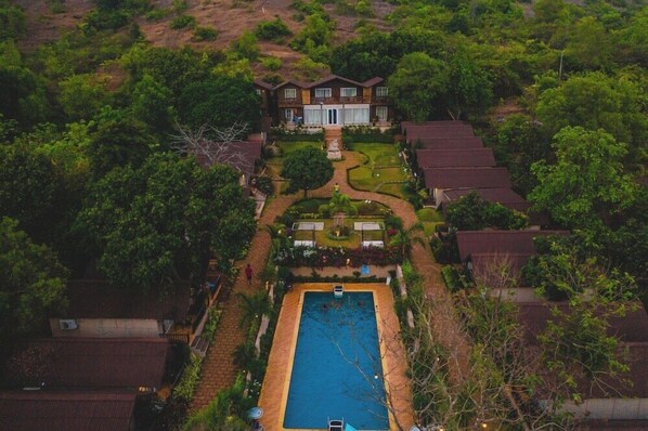 A large house with a swimming pool, surrounded by lush greenery and a well-maintained garden. - Stone Wood Resort & Spa (Mandrem)