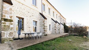 A stone building with a patio area, a table, and chairs. - The Monastery - ORBAIS L'ABBAYE (ORBAIS L'ABBAYE)