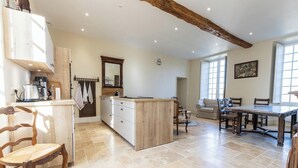 A spacious kitchen with a central island, wooden chairs, a dining table, and a large window. - The Monastery - ORBAIS L'ABBAYE (ORBAIS L'ABBAYE)