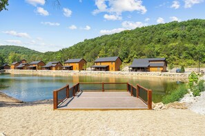 Ein Seehotel mit Holzhütten, einem Steg und bewaldetem Hintergrund.