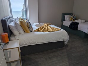 Ein Hotelzimmer mit Bett, Meerblick, Nachttisch und Fenster.
