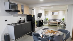 Eine moderne Küche mit Gasherd, schwarzem Kühlschrank, Mikrowelle und einem Essbereich mit Glastisch und Stühlen.