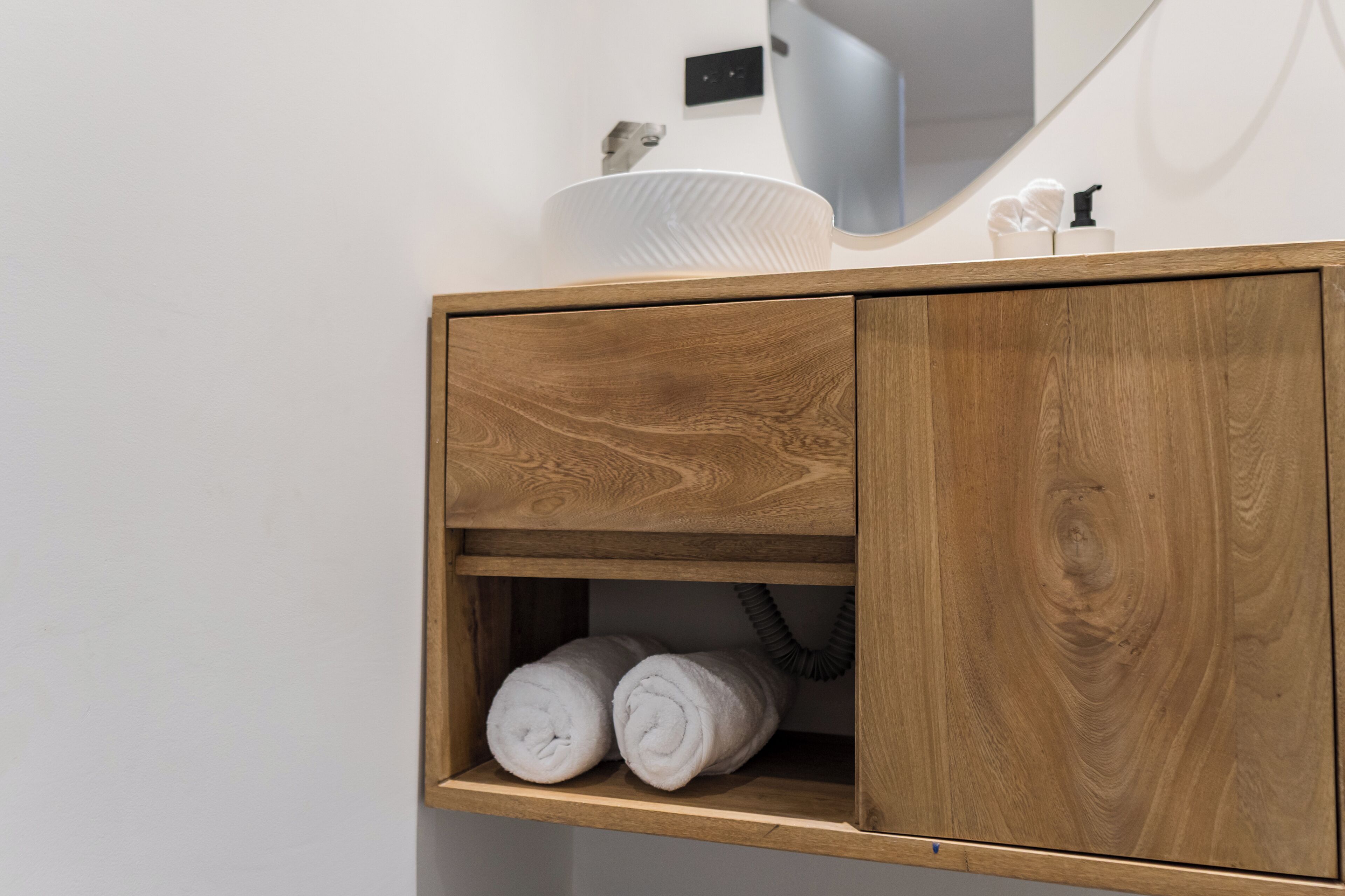 Un tocador de madera con un lavabo blanco, un perchero para toallas y un espejo.
