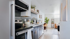 A modern kitchen with a built-in oven, microwave, and a large island with a sink. - Sleeps 12 · 3-Kitchen · Walk to Link Light Rail (Seattle)