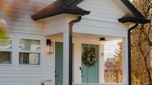 A white house with a porch, a green door, and a 'B' sign on the wall. - Sleeps 12 · 3-Kitchen · Walk to Link Light Rail (Seattle)