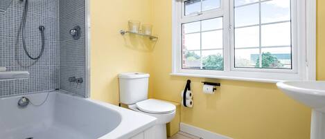 A bathroom with a bathtub, toilet, and window.