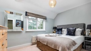 A bedroom with a bed, dresser, window, and a mirror. - The Fox at Hurley - The Warren Suite (Maidenhead)