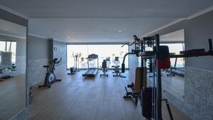 Een sportschool met cardioapparatuur, gewichthefmaterialen en een groot raam met uitzicht op de omgeving.