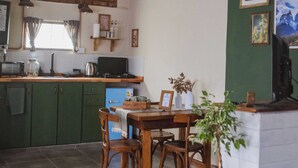 A kitchen with green cabinets, a dining table with chairs, a coffee machine, and a TV.